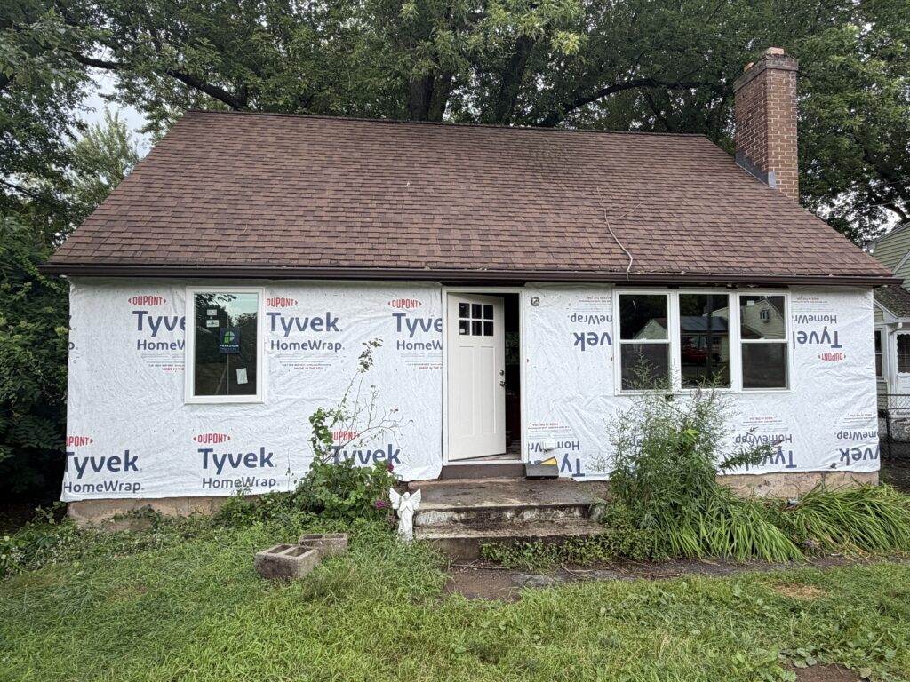 During: house wrapped in Tyvek weather barrier with new windows and front door installed, Bristol CT